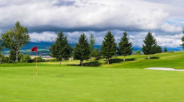 Green golf course with clouds overhead