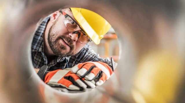 man in hardhat die een drukmeter aanpast