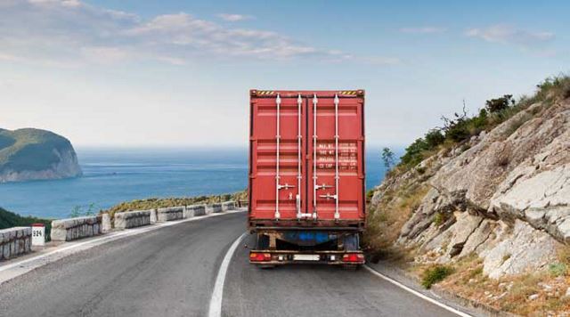 semi truck driving on a road by the ocean