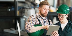 Image of two employees working in manufacturing industry looking at a tablet