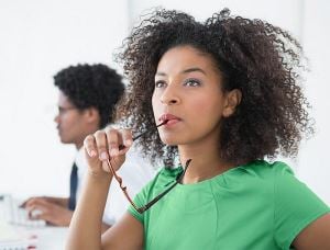 Femme en pleine réflexion tenant ses lunettes