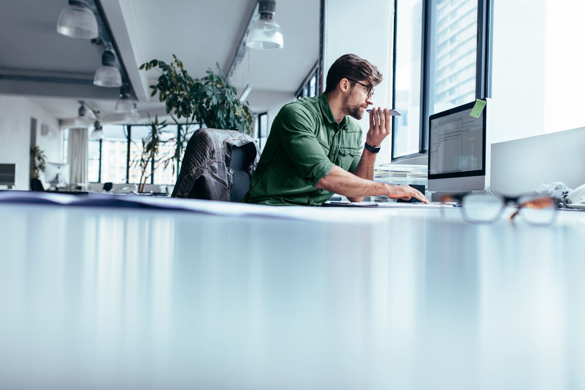 man at the office sitting at his desk speaking into his cell phone