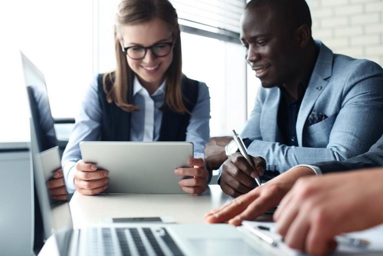 Billtrust White Paper: male and female coworker looking at a tablet, third coworkers hands in foreground