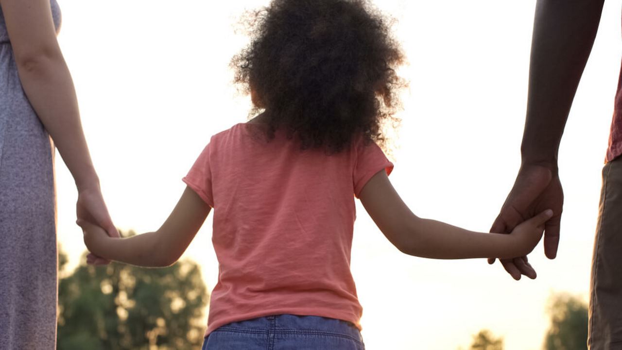 child holding the hands of her parents