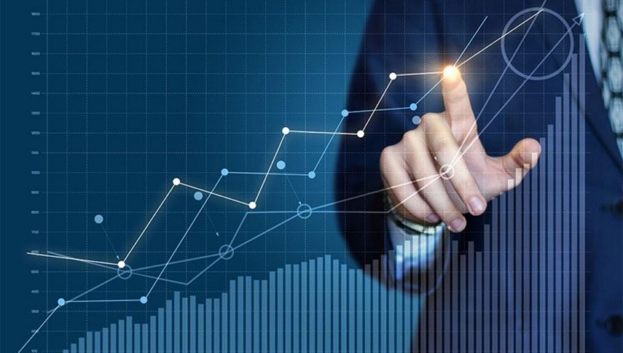 Close-up of hand with a glowing fingertip drawing a chart increasing in value