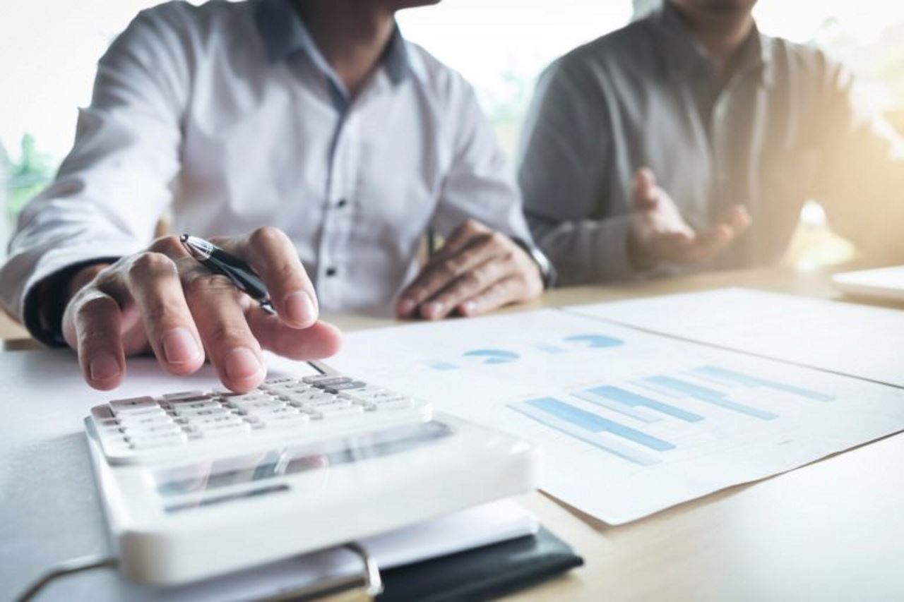 two employees at a table calculating numbers and looking at data in front of them