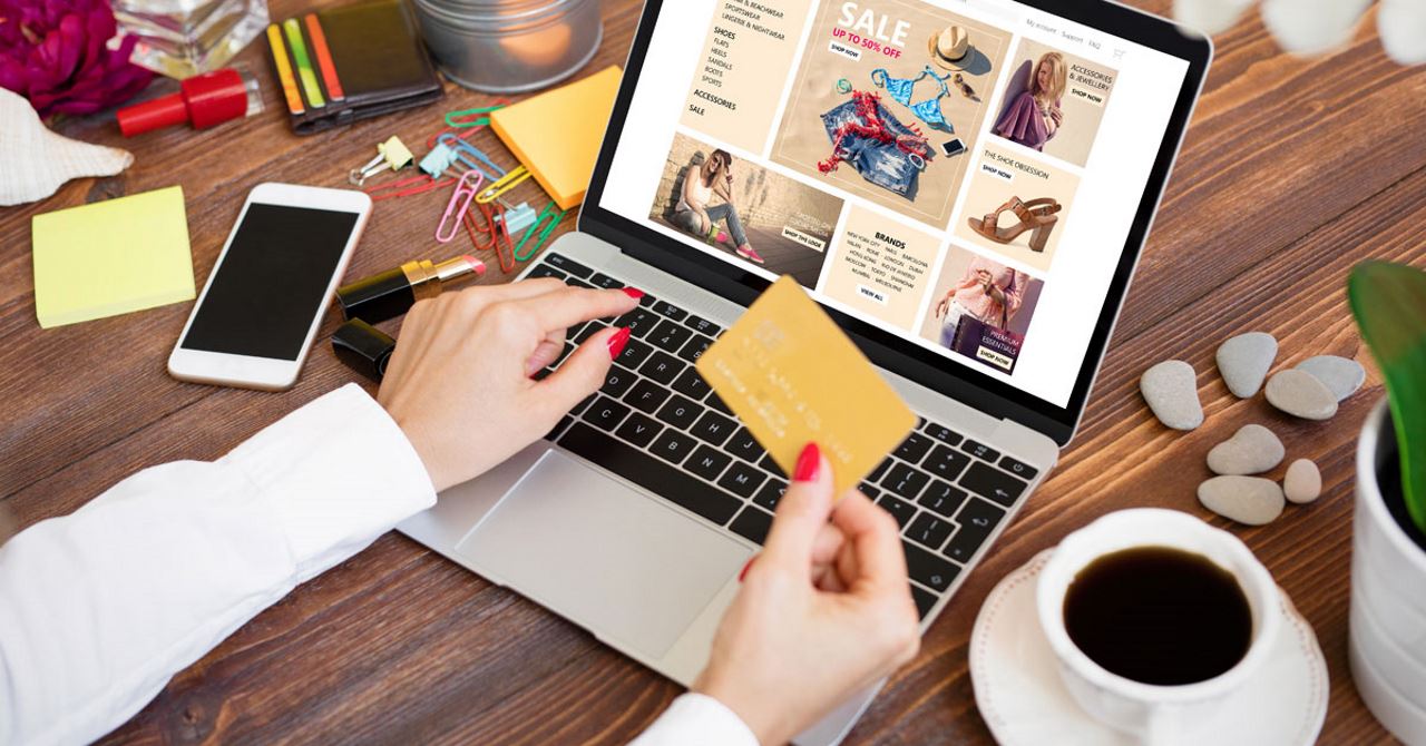 woman's hands holding a credit card and shopping online on a laptop at desk