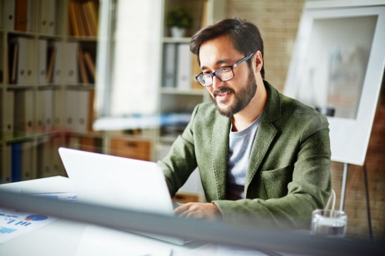 man sitting in an office working on a laptop