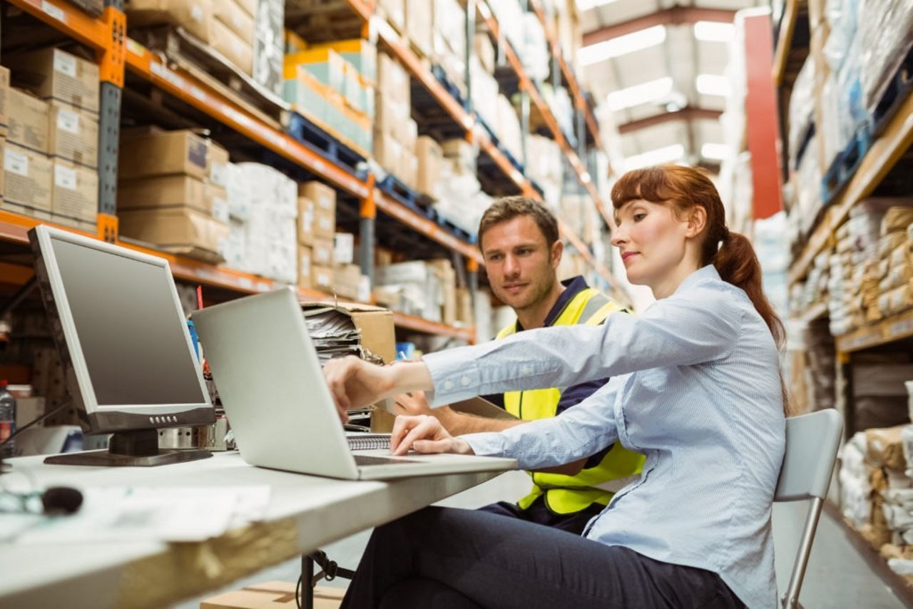 team members set up in a warehouse reviewing customer orders on a laptop