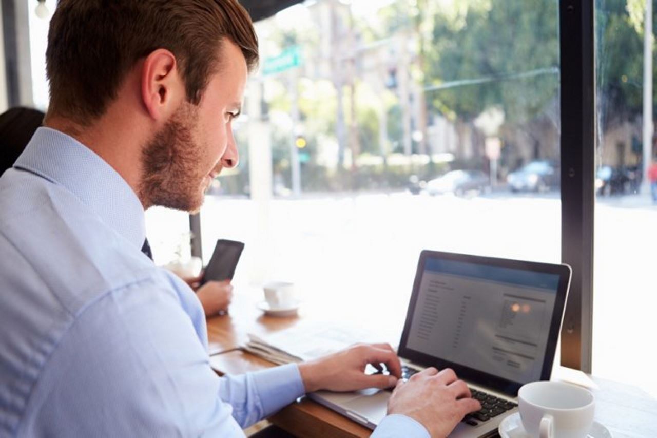 Mann, der im Café am Laptop arbeitet