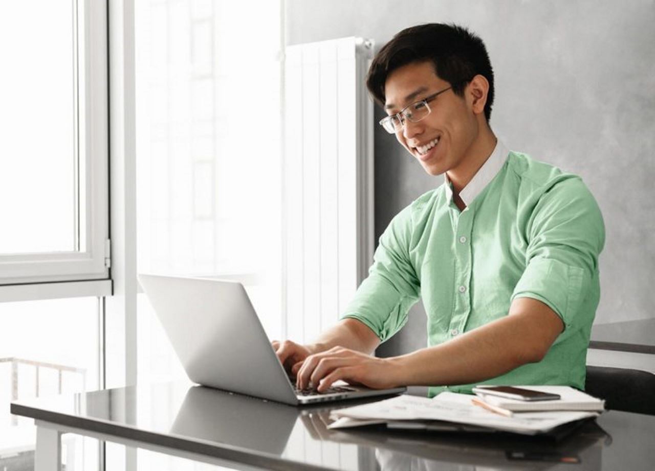 man in office smiling and working on laptop