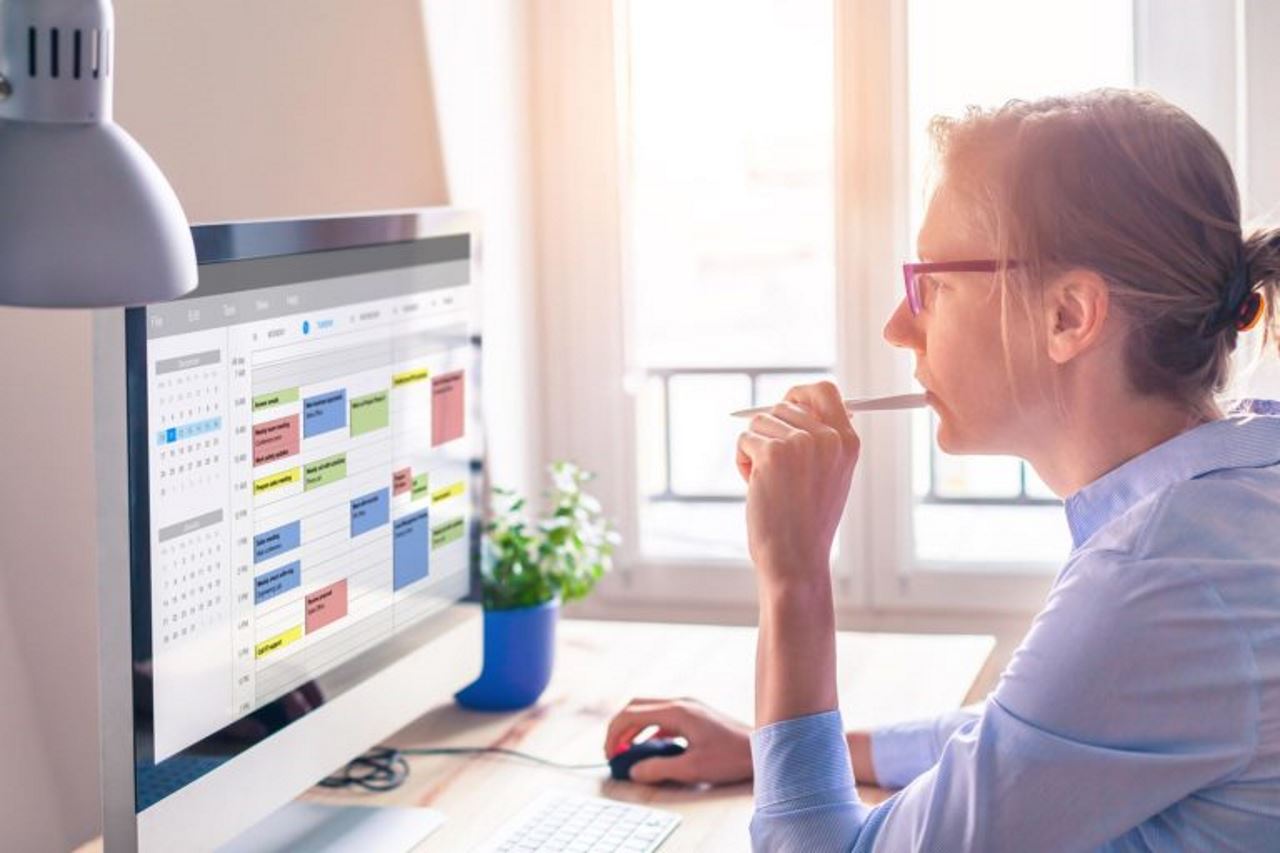 woman in her home office looking at her calendar on desktop computer