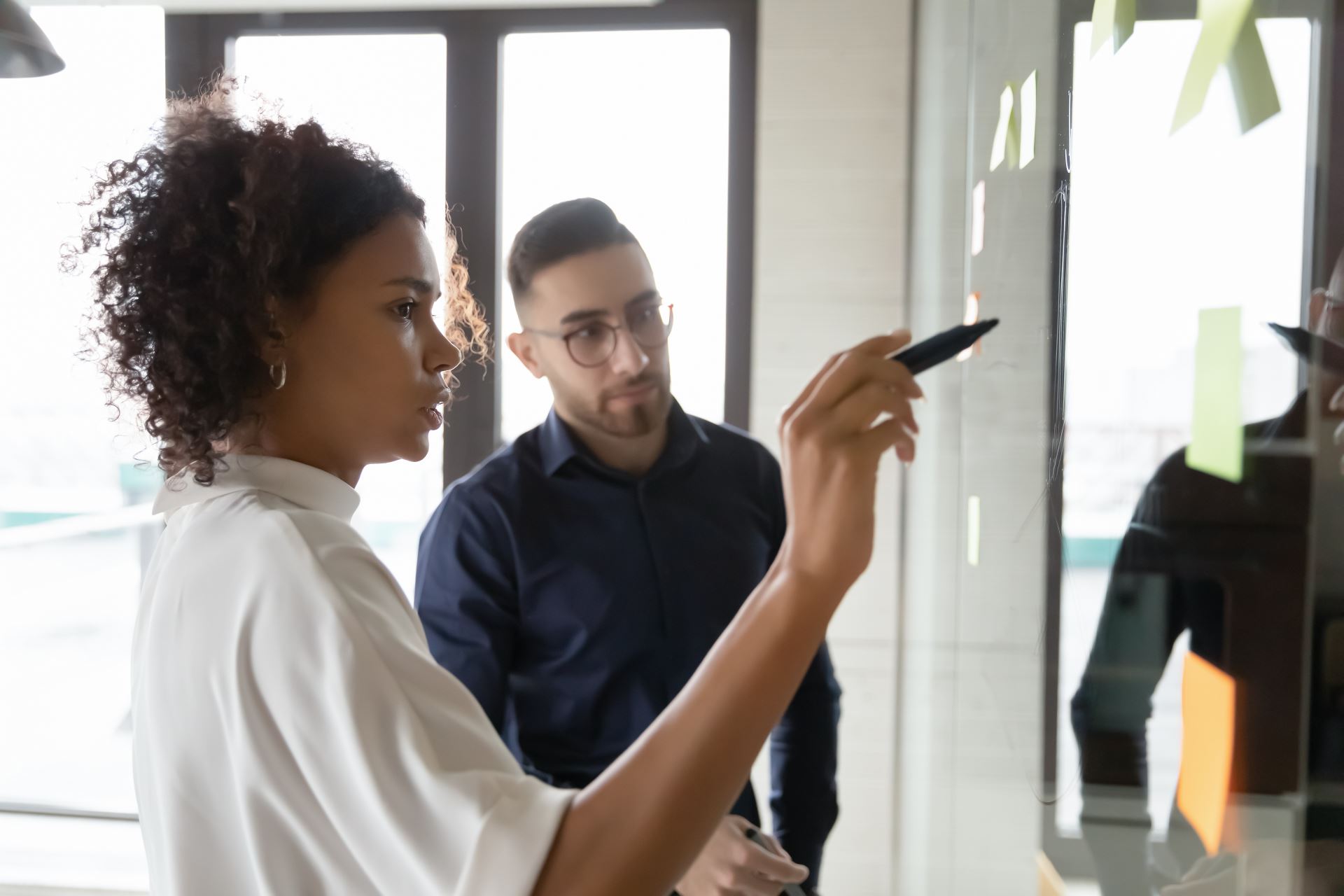 man and woman having a discussion and looking at sticky notes on a wall