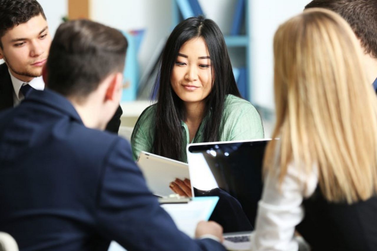 Professional woman in meeting looking at a tablet and smiling