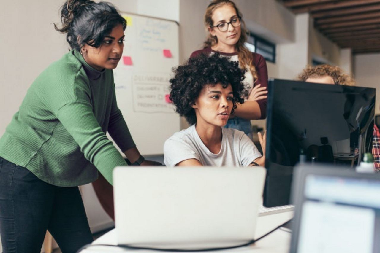 employees viewing a co-worker's computer screen in her office