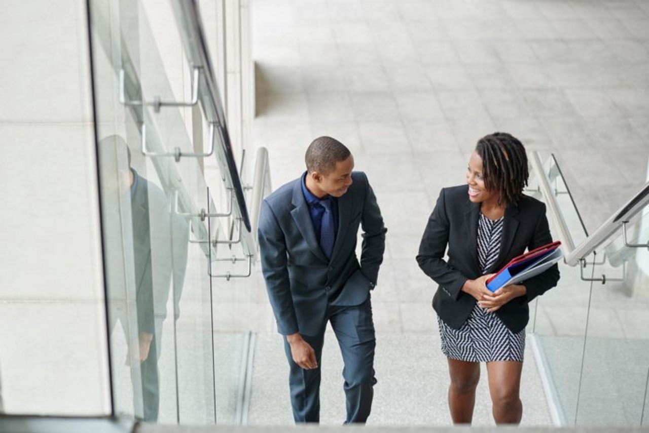 Two Black colleagues walking up the stairs and chatting