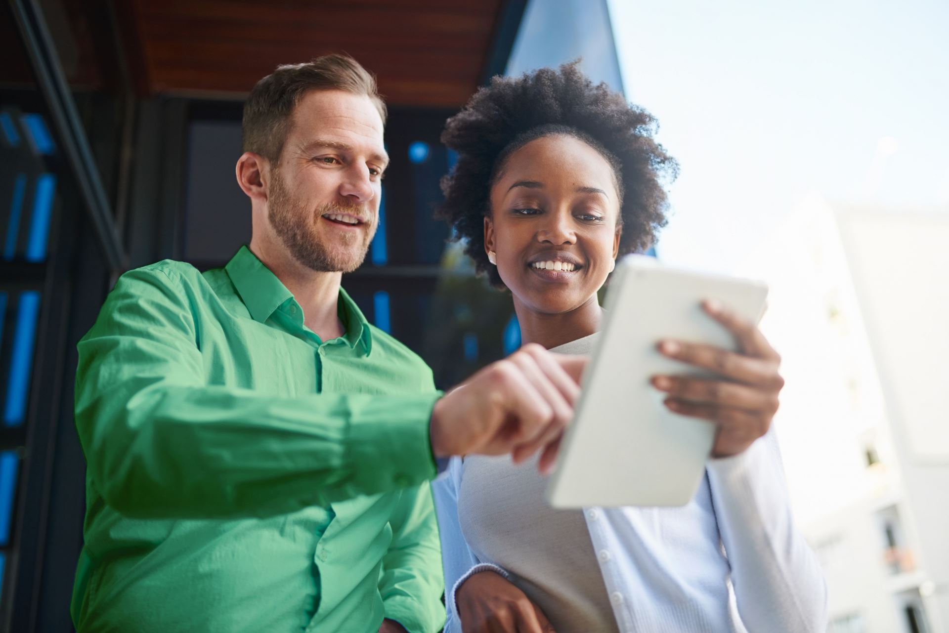 Two people talking and pointing at a tablet