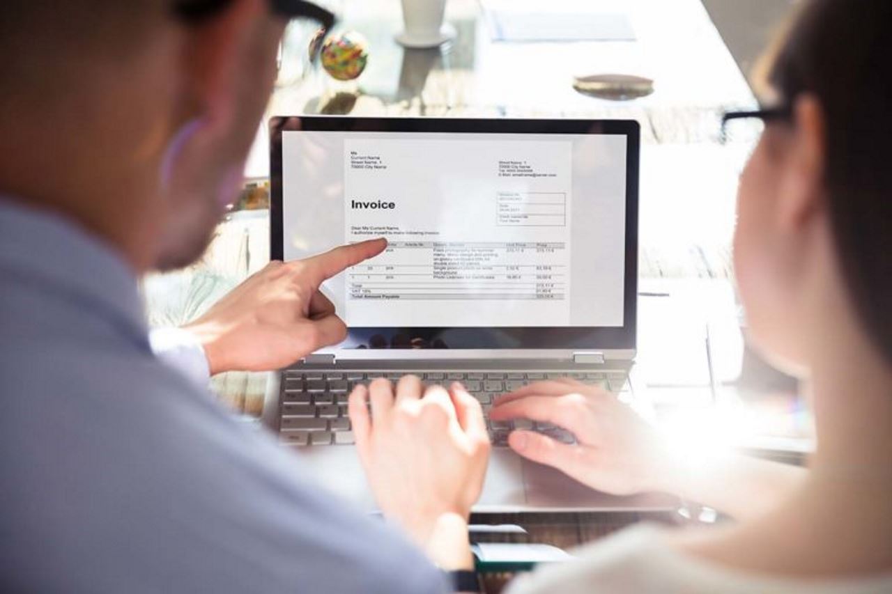 two employees reviewing an invoice on a laptop screen