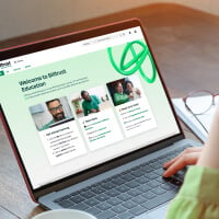Persoon die naar een laptop kijkt terwijl de Billtrust Customer Education-portal wordt weergegeven
