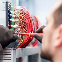 Electrician using a screwdriver on an electric panel