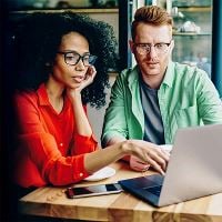 Man and woman looking at computer together in coffee shop