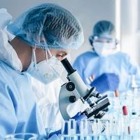 Scientist looking through microscope in clean room