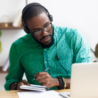 Un homme assis devant un ordinateur prend des notes et apprend