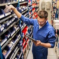 Man in car parts warehouse looking at tablet