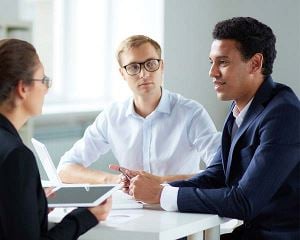 Trois collaborateurs en pleine conversation autour d'une table