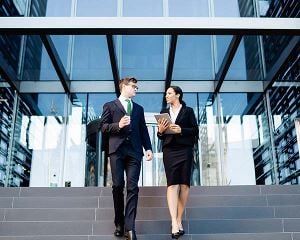 Corporate man and woman walking down the front stairs of an office building
