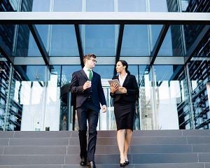 Corporate man en -vrouw die de trap aan de voorkant van een kantoorgebouw aflopen