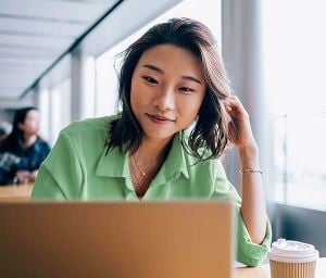 Frau, die im Café auf einen Computer schaut