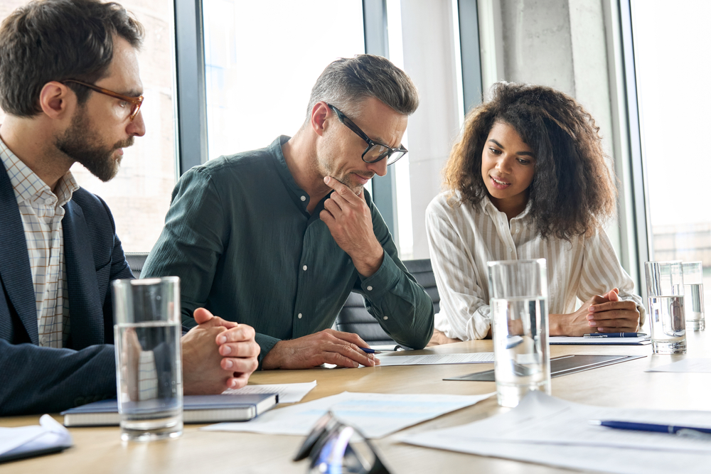 Focused mature businessman with two younger colleagues