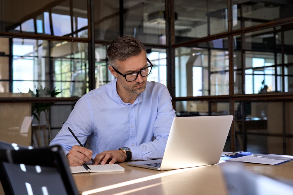 Professional looking at laptop and taking notes