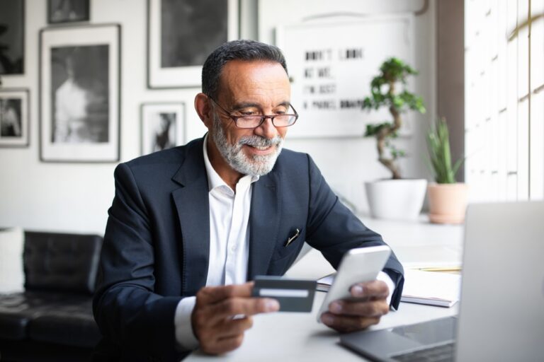 Older professional man paying with credit card on mobile device