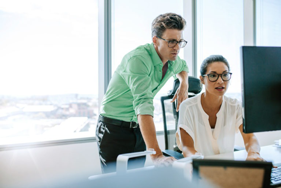 two people working over desk table