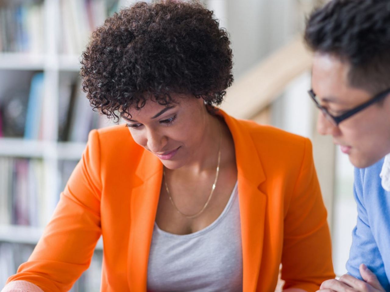 An image of a professional woman and man looking down at something and discussing together