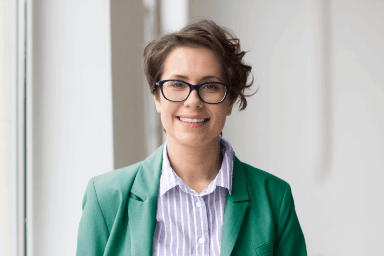 Women in green outfit wearing glasses smiling