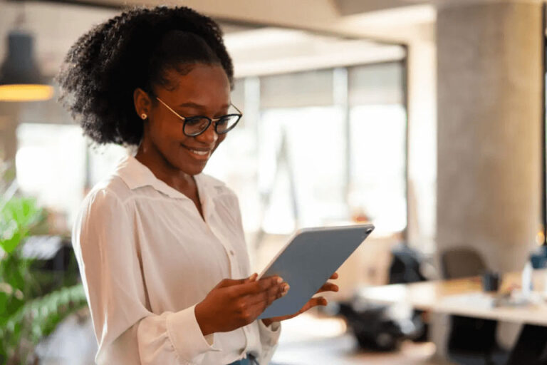 Women wearing glasses in a white short holding a tablet in office