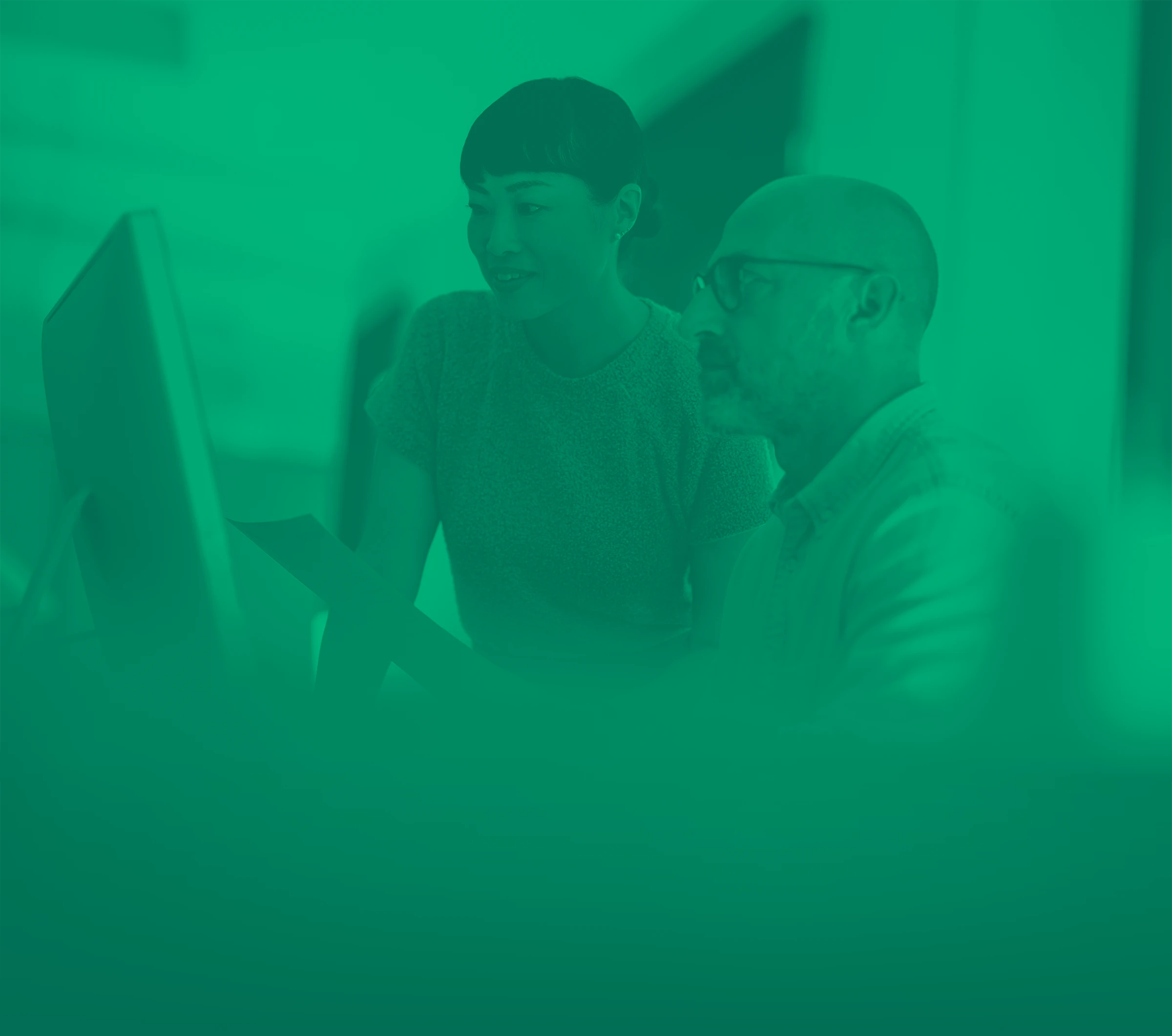 Women and man in office looking at computer screen