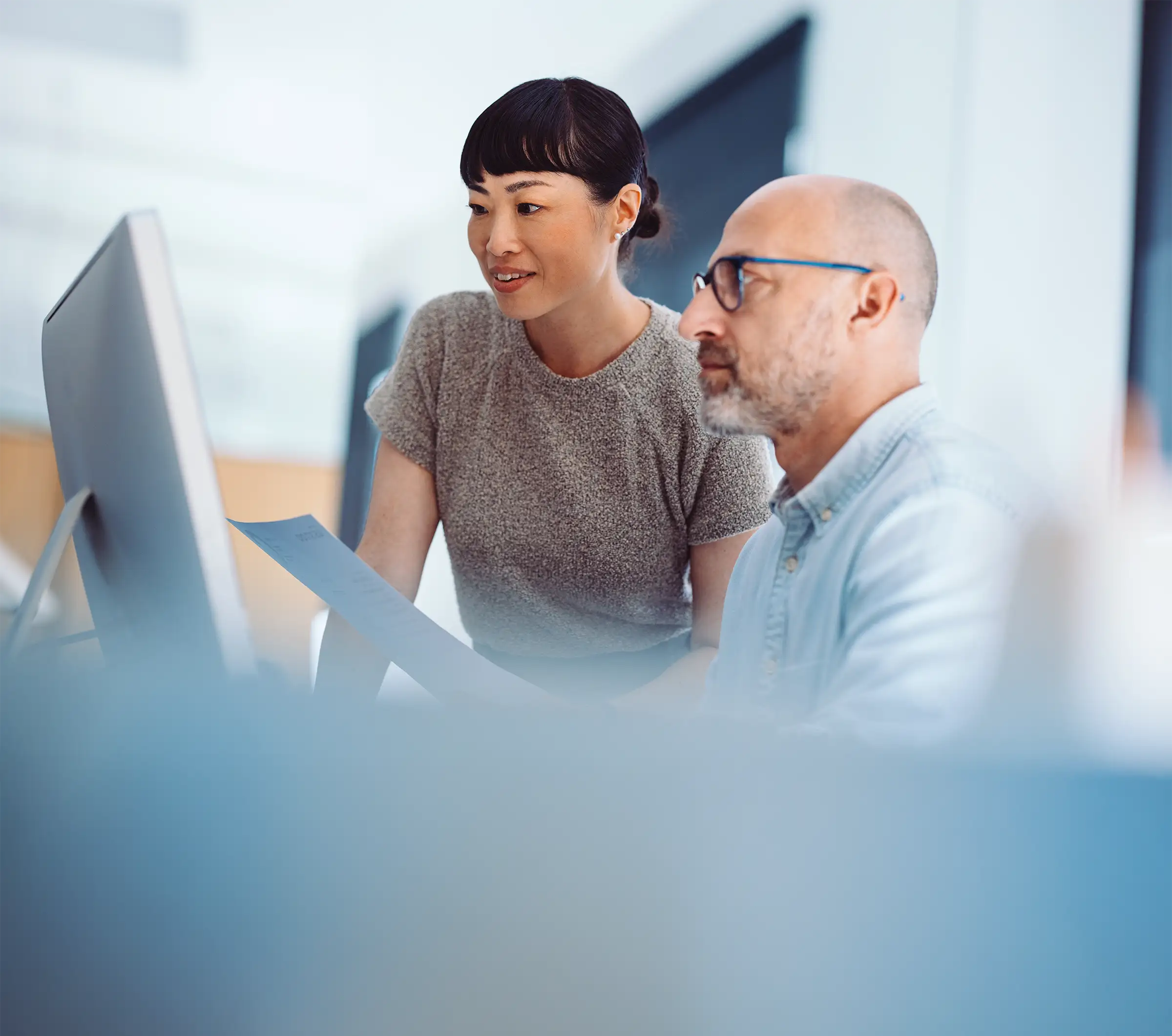 Women and man in office looking at computer screen