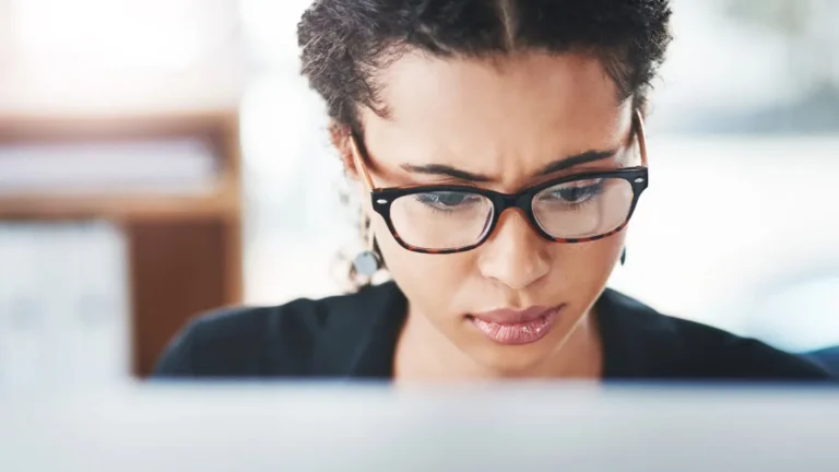 woman wearing glasses looking at computer