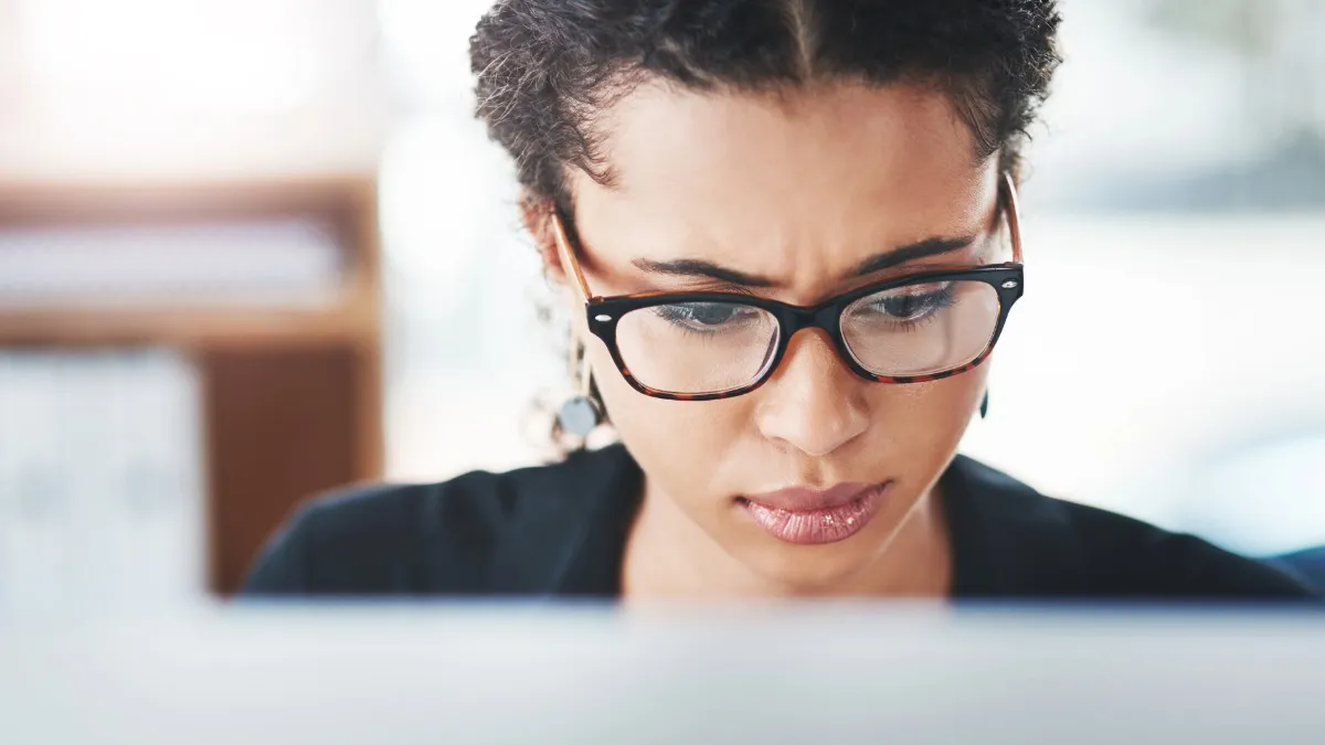 woman wearing glasses looking at computer