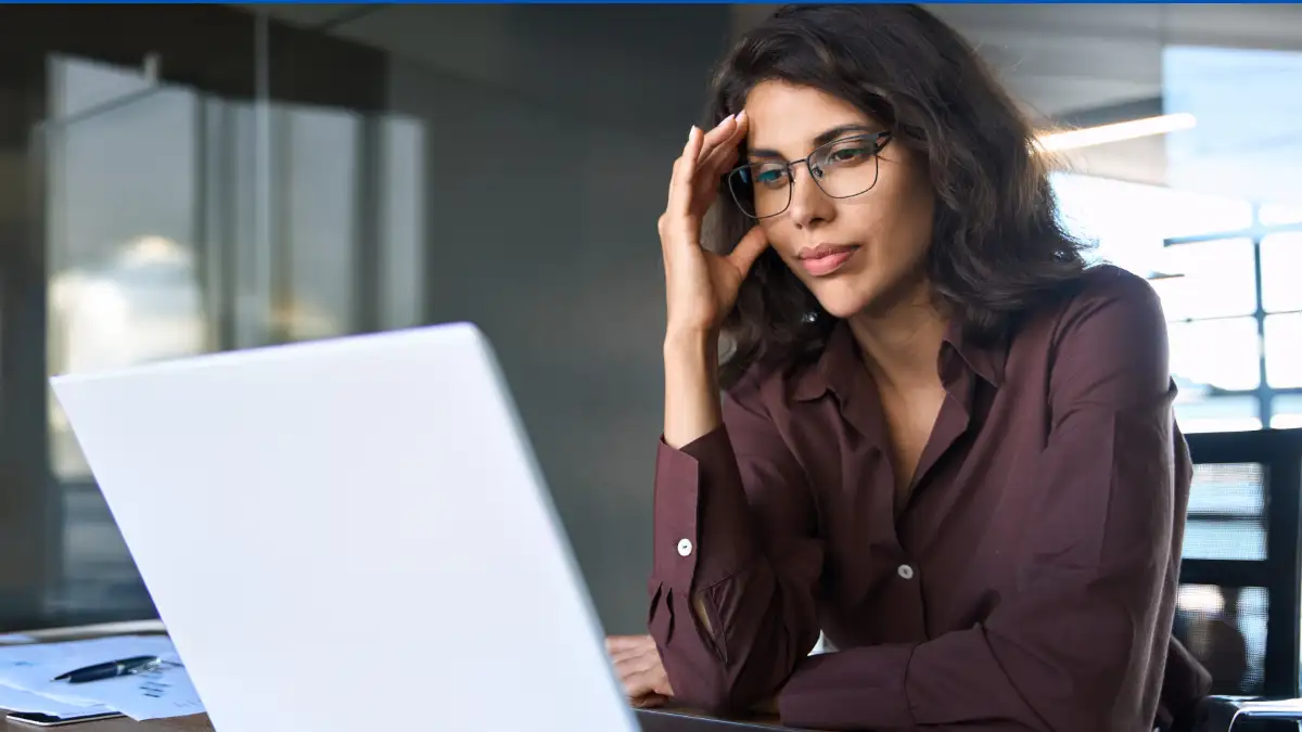 woman wearing glasses looking at laptop thinking deeply