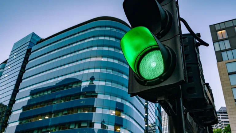 green street sign with city buildings in background