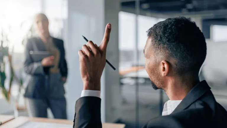 man in office raising hand holding pen to speak