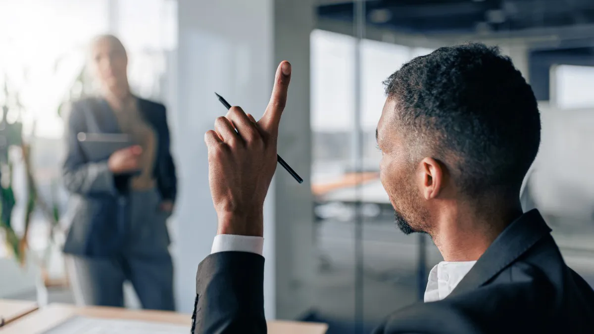 man in office raising hand holding pen to speak