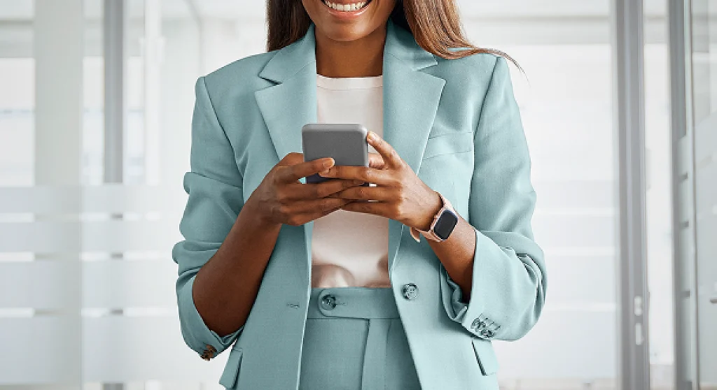 Professional young woman wearing a light blue suit holding a cellphone