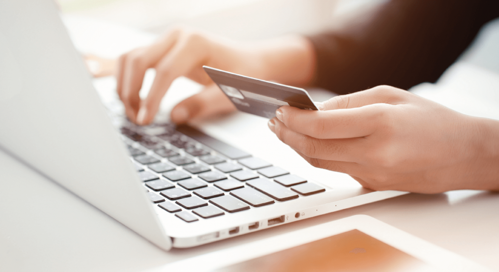 Closeup view of person holding a credit card while typing on a laptop