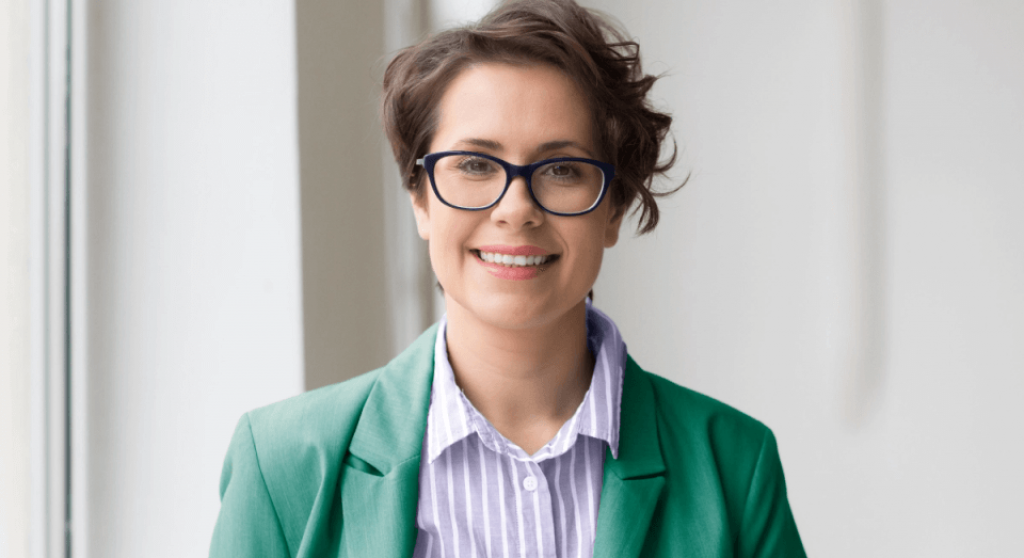 Women in green outfit wearing glasses smiling